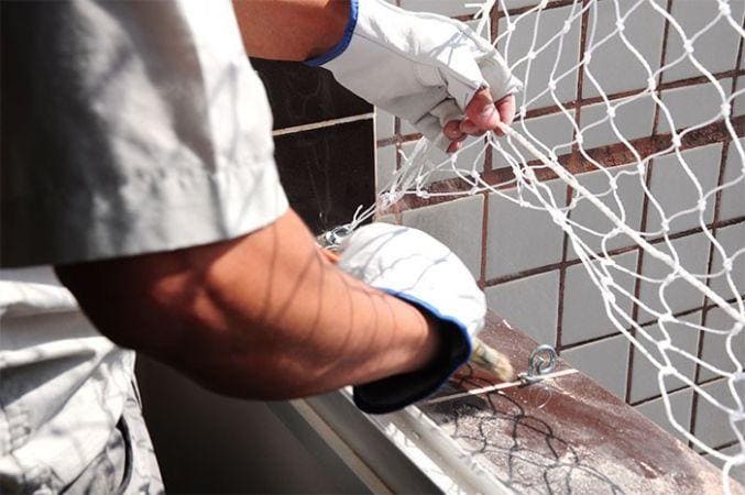Técnico fazendo instalação de redes de proteção em SJC